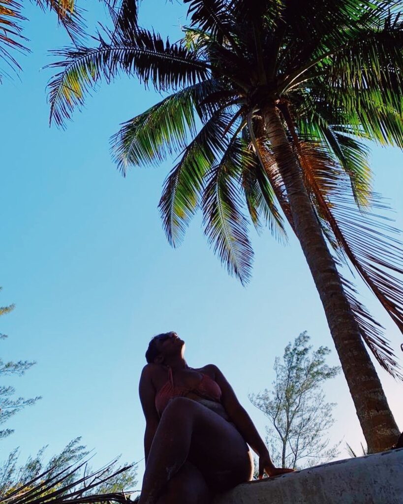 girl in bikini under a palm tree and blue skies