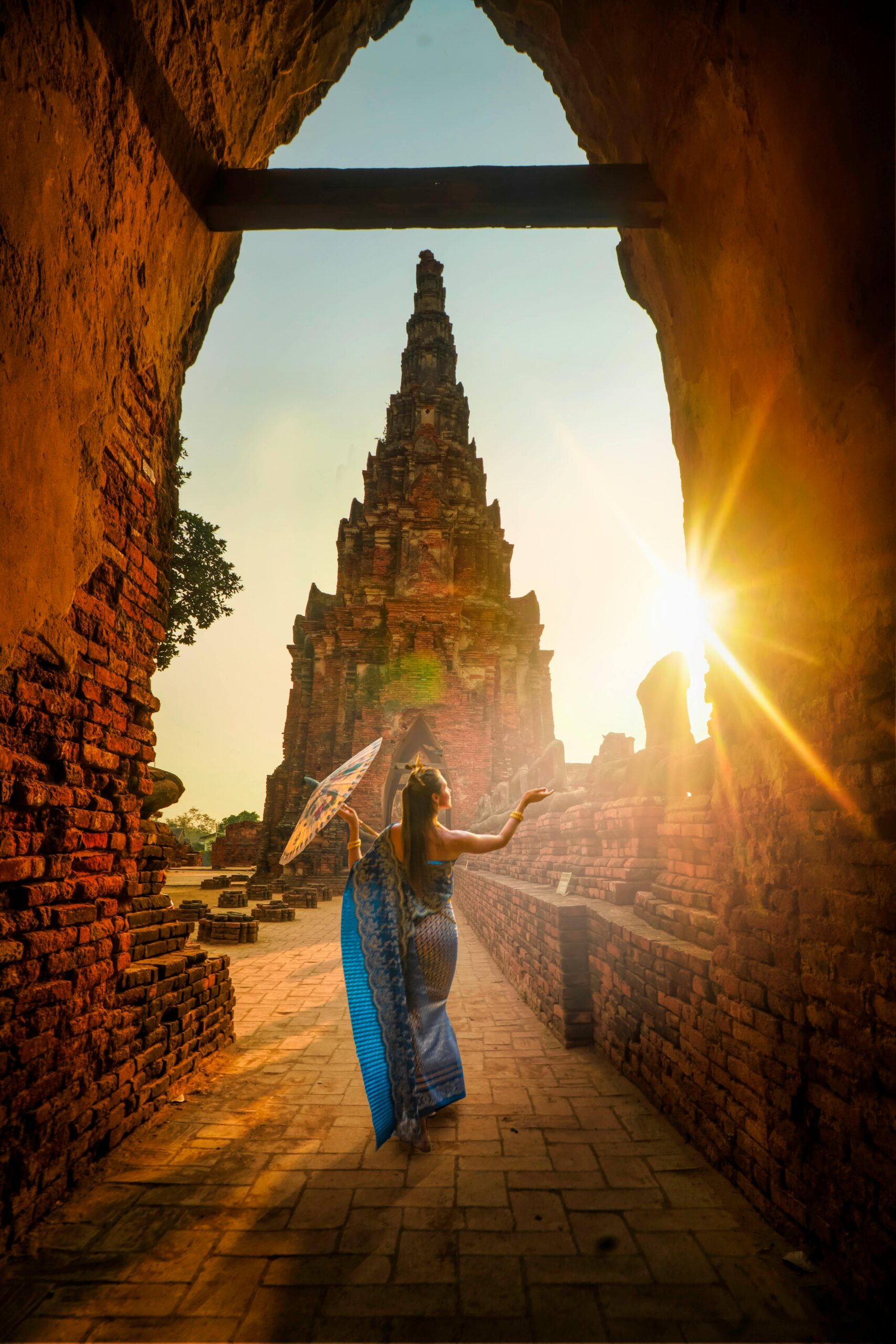 a woman in a blue dress holding an umbrella in a stone archway